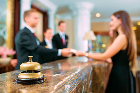 Credit Card ACH Processing in Florida for Hotels and Resorts, in photo front lobby counter at a Hotel taking a credit card payment from a woman.